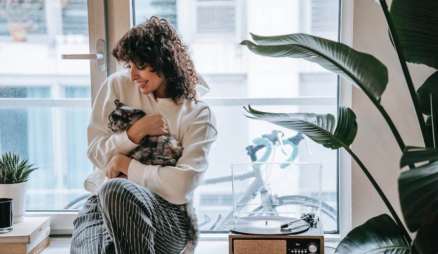 Besitzerin kuschelt mit Katze vor Fenster